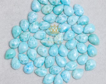 May include: A collection of light blue teardrop-shaped gemstones with white marbling. The gemstones are arranged on a light gray surface. The image includes the text "LUXE HOUR" in gold.