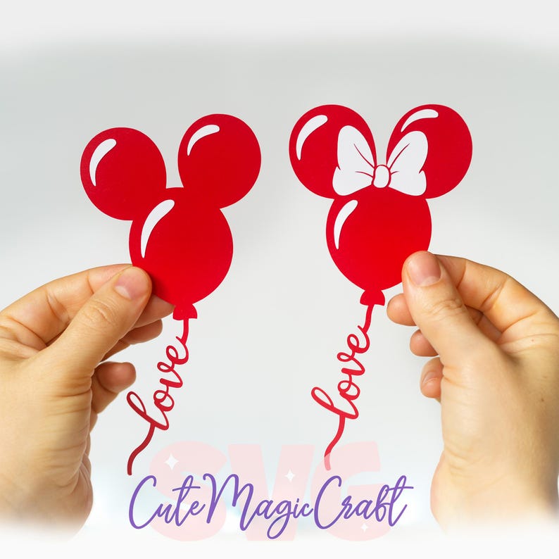 Puede incluir: Dos recortes de globos rojos con forma de Mickey Mouse, uno con un lazo blanco, sostenidos por manos. Cada globo tiene la palabra "love" en escritura cursiva. El texto "Cute Magic Craft" est&aacute; en la parte inferior en morado.