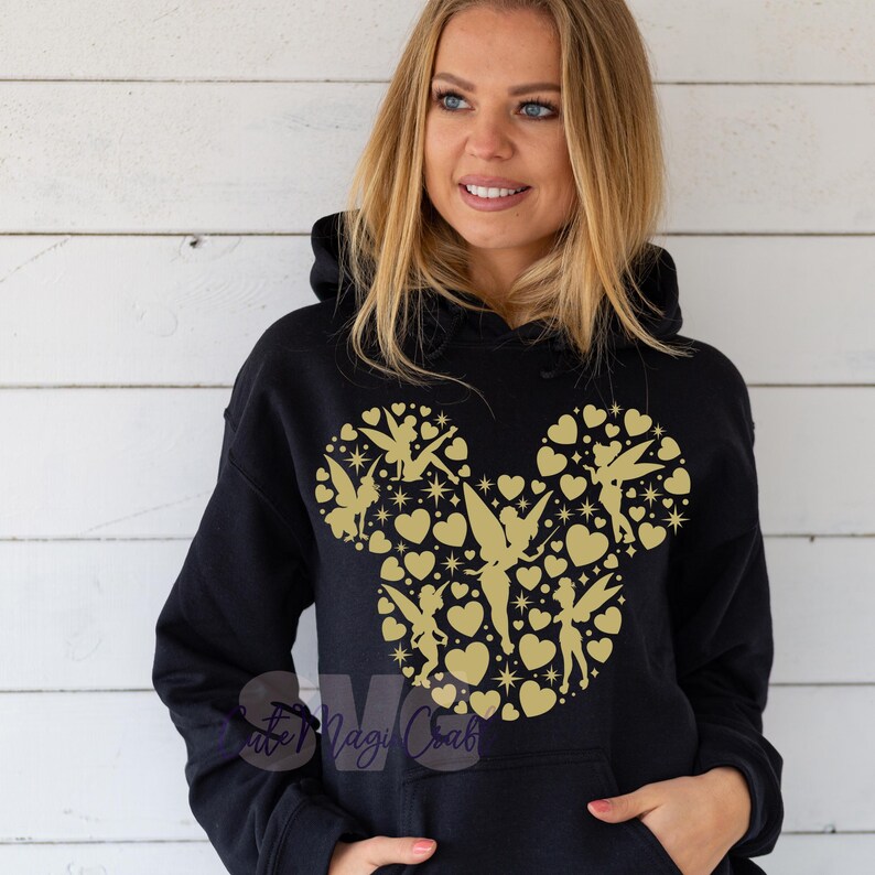 May include: Black hoodie with a gold Mickey Mouse head design. The design is made up of hearts, stars, and fairy silhouettes. The sweatshirt has a front pocket and a drawstring hood.