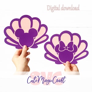 May include: Two purple and light pink seashell-shaped cutouts, each featuring a Mickey Mouse or Minnie Mouse silhouette. The text "Digital download" is at the top, and "Cute Magic Craft" is at the bottom. The cutouts are held by hands.