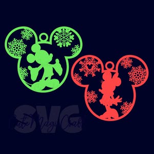 Könnte beinhalten: Zwei Disney-Weihnachtsschmuckstücke. Eines ist grün mit Mickey Mouse im Inneren, das andere ist rot mit Minnie Mouse. Beide sind wie Mickey Mouses Kopf geformt und haben Schneeflocken-Ausschnitte. Der Text "Cute Magi Craft" befindet sich unten.