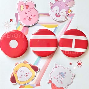 May include: A collection of colorful stickers and red button pins. The stickers feature cartoon animal characters in pink, yellow, and white. The button pins are red with white stripe and bar designs. Decorative star accents are also present.