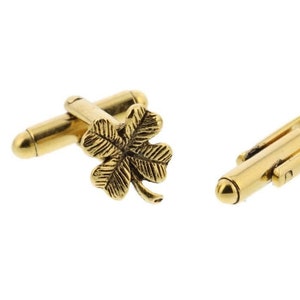 May include: A pair of gold-toned cufflinks featuring a four-leaf clover design.