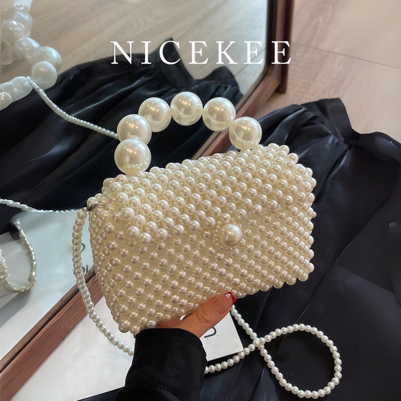 May include: A rectangular, off-white beaded handbag with a pearl handle and a long pearl strap. The bag is covered in small, round beads and features a large pearl clasp. The word "NICEKEE" is printed in white at the top.