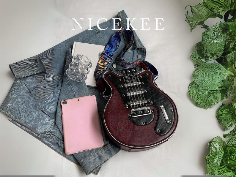 May include: A burgundy and black guitar-shaped handbag with a patterned strap rests on a denim jacket. A pink tablet, a small white book, and a clear glass object are also present. The word "NICEKEE" is at the top.