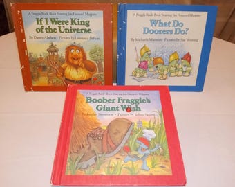 May include: Three vintage children's books featuring colorful illustrations and text. The titles include "If I Were King of the Universe," "What Do Doozers Do?," and "Boober Fraggle's Giant Wish." The books have red, orange, and blue covers.