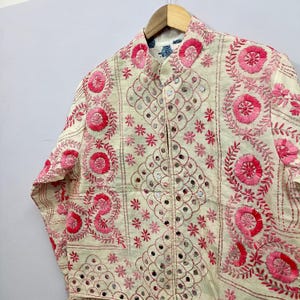 Beautiful floral motifs, geometric embroidery patterns, and handcrafted mirror accents create a rich textured look perfect for bohemian fashion lovers, festival outfits, Indo-western styling, vacation wear, casual layering, and sustainable artisan fashion collections.