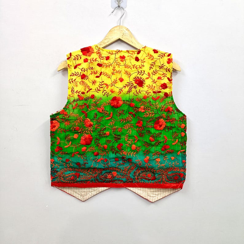 May include: A sleeveless vest featuring a vibrant ombre gradient transitioning from yellow at the top to green and teal at the bottom. The garment is adorned with intricate red floral embroidery and vine patterns, finished with a red hem and a light beige lining.