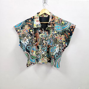 Op de afbeelding: Een jack met korte mouwen voorzien van een levendig, meerkleurig paisley- en bloemenpatroon op een zwarte achtergrond. Het kledingstuk heeft een klassieke kraag, een knoopsluiting aan de voorzijde en zichtbare stiksels in kantha-stijl.