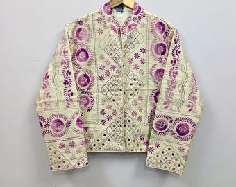 May include: A cream-colored jacket featuring intricate purple floral and circular embroidery patterns throughout the front and sleeves. The garment is accented with small, reflective circular mirrors embedded within the stitched designs.