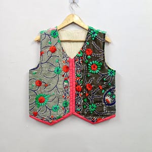 Handmade colorful Indian embroidered vest with contrasting grey and black fabric panels, detailed floral and leafy embroidery in green, red, orange and blue, V-neck sleeveless design and bright pink edging, perfect for boho fashion, ethnic outfits, festivals, vacations and everyday layering.
