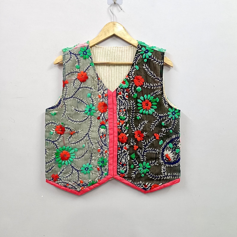 Handmade colorful Indian embroidered vest with contrasting grey and black fabric panels, detailed floral and leafy embroidery in green, red, orange and blue, V-neck sleeveless design and bright pink edging, perfect for boho fashion, ethnic outfits, festivals, vacations and everyday layering.