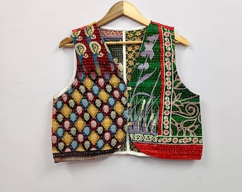 May include: A sleeveless vest featuring a patchwork design with a variety of colorful patterns. The left side displays a diamond motif in red, yellow, and blue, while the right side features green fabric with floral and botanical prints. Three buttons.