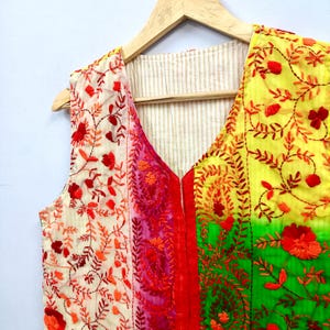 The vest combines cream, pink, yellow, green and turquoise tones with rich red embroidery for a unique, colorful artisan look.