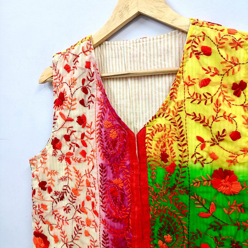 The vest combines cream, pink, yellow, green and turquoise tones with rich red embroidery for a unique, colorful artisan look.