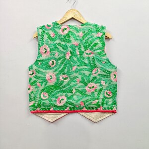 unique sleeveless waistcoat features beautiful floral and leafy embroidery in bright green, red, orange and blue over contrasting grey and black fabric panels.
