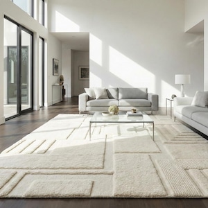 May include: A large, rectangular area rug in an off-white, cream color featuring a textured, geometric pattern of raised, varying rectangular shapes and lines that create a three-dimensional effect across the entire surface of the floor covering.