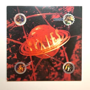 May include: Album cover for the Pixies' "Bossanova" album. It shows a red planet with the band's name in a neon font. The background is dark with red lines and circular elements. The word "Bossanova" is also visible.
