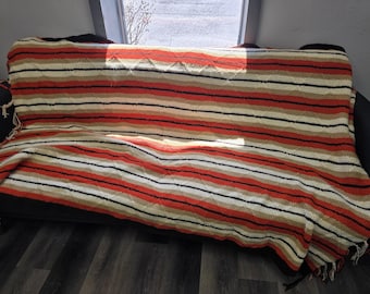 Vintage handmade afghan blanket featuring a striped crochet pattern in orange, cream, brown, and tan 1970s