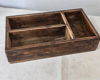 Antiguo utensilio primitivo de madera con tres compartimentos y contenedores de almacenamiento.