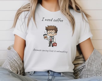 May include: White t-shirt with the text "I need coffee" above a cartoon doctor holding a coffee cup and a medical bag. The text "Because saving lives is exhausting" is below the illustration.