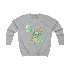 Puede incluir: Una sudadera gris claro con una ilustraci&oacute;n de acuarela de un dinosaurio verde con gafas y un gorro de fiesta. Un globo verde con el n&uacute;mero 5 est&aacute; a la izquierda. El nombre "Levo" est&aacute; escrito en cursiva. Una piruleta colorida est&aacute; a la izquierda.