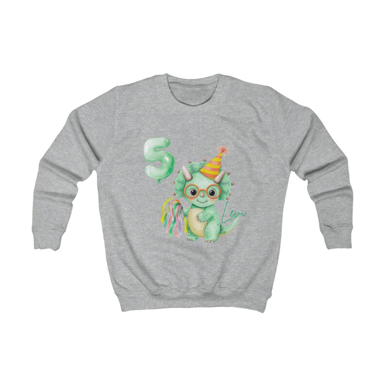 Puede incluir: Una sudadera gris claro con una ilustraci&oacute;n de acuarela de un dinosaurio verde con gafas y un gorro de fiesta. Un globo verde con el n&uacute;mero 5 est&aacute; a la izquierda. El nombre "Levo" est&aacute; escrito en cursiva. Una piruleta colorida est&aacute; a la izquierda.