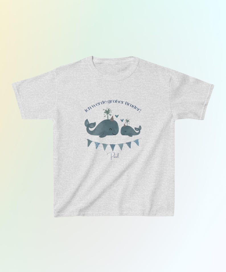 May include: A light gray short-sleeve t-shirt featuring a graphic of two blue whales wearing party hats, with a blue bunting banner below them. The text "Ich werde gro&szlig;er Bruder!" is printed above the whales, and the name "Paul" is below.