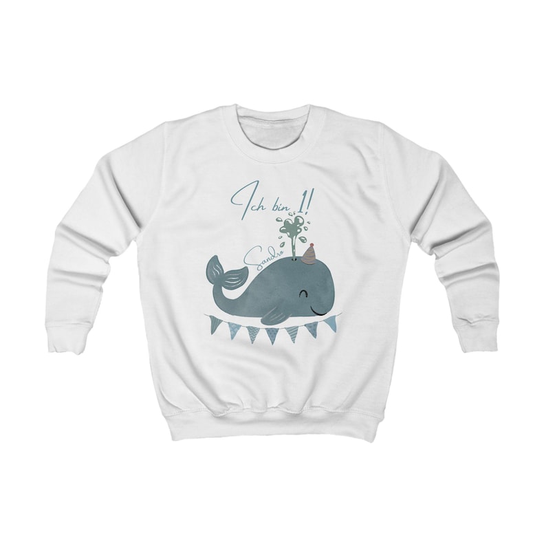 May include: White sweatshirt featuring a blue whale illustration with a party hat and banner. The text "Ich bin 1!" and a name are written above the whale. A cute and festive design for a child's first birthday.