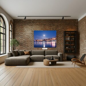 a modern living room with a large sectional sofa, a wooden coffee table, and a bookshelf. The room has a brick wall and a large window, creating a cozy and inviting atmosphere. A large painting of a city skyline is displayed on the wall, adding an artistic touch to the space.