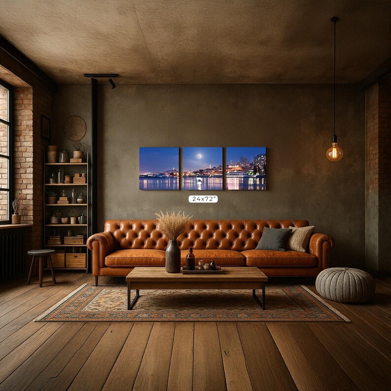 a cozy living room with a large brown leather sofa, a wooden coffee table, and a brick wall with a painting of a city skyline.