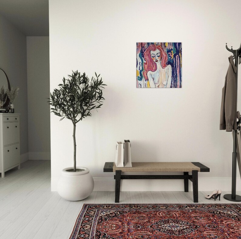 May include: An abstract painting of a woman with pink hair and closed eyes. The artwork features a colorful background with blue, yellow, and purple hues. The painting is displayed on a white wall in a well-lit room.