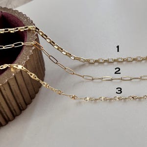 May include: Three gold-toned metal chains labeled 1, 2, and 3. Chain 1 features a square link design, chain 2 consists of elongated oval links, and chain 3 displays a delicate pattern of small, textured, star-like circular links.