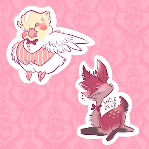 Puede incluir: Dos pegatinas sobre un fondo rosa. Una es un pájaro de dibujos animados con pajarita y chaleco. La otra es un ciervo de dibujos animados con el texto "SMILE DEER". Ambas pegatinas tienen un borde blanco.