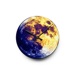 May include: Round wall clock featuring a vibrant depiction of the moon. The clock face is split, with one half in deep blue and the other in shades of yellow and orange. Black clock hands indicate the time.