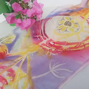 May include: A vibrant silk scarf with a floral pattern in pink, yellow, and red hues. The scarf showcases a large, stylized flower at its centre, encircled by abstract forms and designs. The backdrop is a blend of purple and blue.