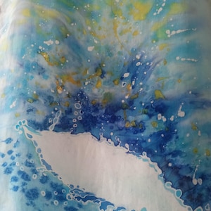 May include: Abstract textile art with a watercolour effect. The design features a blend of blues, yellows, and whites, creating a dynamic, fluid pattern. The colours are layered, with splashes and splatters adding texture and depth to the fabric.