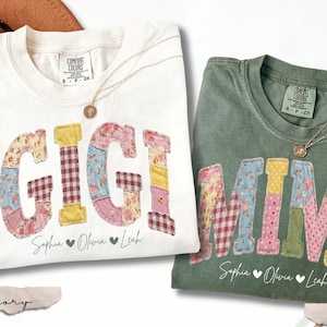 May include: Two Comfort Colors t-shirts, one ivory and one moss green, with the words "GIGI" and "MIMI" appliqued in patchwork fabric. Each shirt has a gold necklace and the names "Sophia, Olivia, Leah" below. The shirts are 100% cotton.