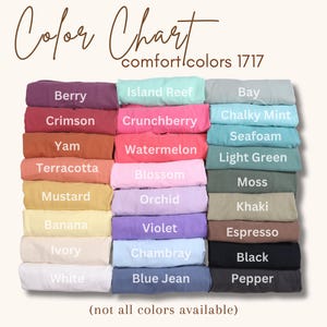 May include: A color chart for Comfort Colors 1717 t-shirts featuring three columns of folded fabric in various shades. Text labels include Berry, Crimson, Yam, Terracotta, Mustard, Banana, Ivory, White, Island Reef, Crunchberry, Watermelon, Blossom, Orchid, Violet, Chambray, Blue Jean, Bay, Chalky Mint, Seafoam, Light Green, Moss, Khaki, Espresso, Black, and Pepper.