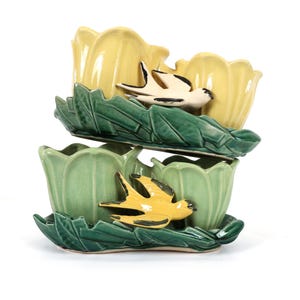 May include: A stacked ceramic planter set featuring two tiers of tulip-shaped vessels. The top tier is pale yellow with a white swallow, while the bottom tier is sage green with a yellow swallow. Both tiers feature dark green molded leaf bases.