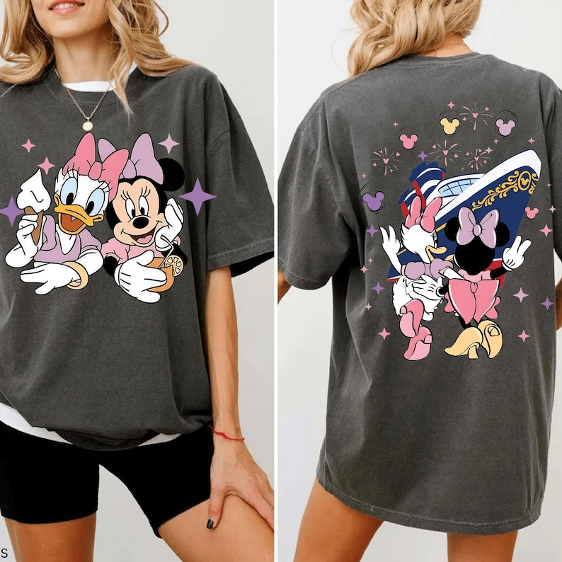 May include: Dark grey t-shirt featuring Daisy Duck and Minnie Mouse. The front graphic shows the characters with ice cream and a drink. The back graphic shows the characters with a cruise ship and fireworks. The shirt has short sleeves and a crew neck.
