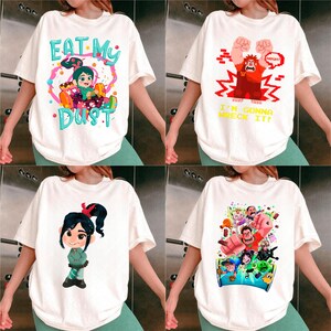 May include: Four white t-shirts with colourful graphics. One shirt says "EAT MY DUST" with a cartoon character. Another says "I'M GONNA WRECK IT!" with a red character. The other two shirts have cartoon character graphics.