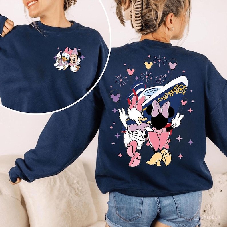 May include: A navy blue sweatshirt with a small embroidered Daisy Duck and Minnie Mouse design on the front. The back features a larger graphic of the characters with a ship, fireworks, and stars. A casual, comfortable style.