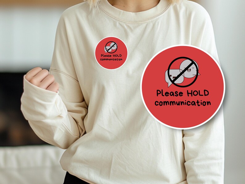 May include: Cream-colored sweatshirt with a round red graphic. The graphic features a speech bubble with a face and a line through it, with the words "Please HOLD communication" in black.