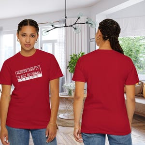 May include: A red t-shirt with the text "ACCOUNTABILITY IS NOT OPTIONAL" in a white rectangular design. The t-shirt is being worn by a person in a well-lit room.