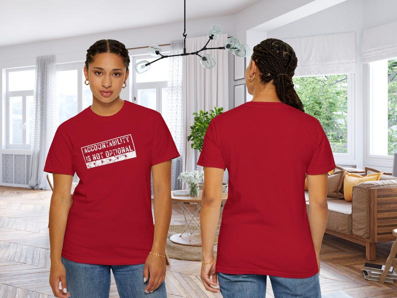 May include: A red t-shirt with the text "ACCOUNTABILITY IS NOT OPTIONAL" in a white rectangular design. The t-shirt is being worn by a person in a well-lit room.