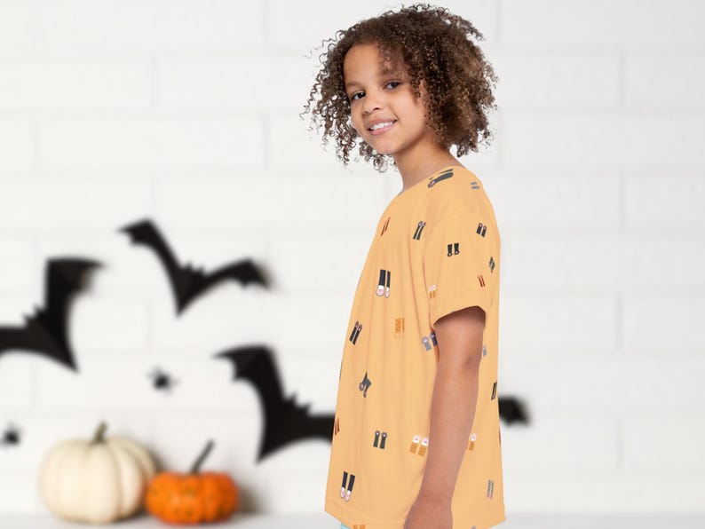 May include: A child wearing a short-sleeved, mustard-colored t-shirt with a repeating pattern of boots. The background features Halloween decorations, including bat silhouettes and pumpkins.
