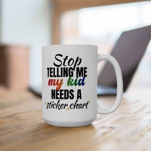 May include: White ceramic mug with the text "Stop telling me my kid needs a sticker chart" in black, red, green, and blue. The mug has a large handle and is decorated with gold stars. A laptop is visible in the background.