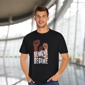 May include: Black t-shirt featuring three raised fists in shades of brown, with the words "REMOVE THE REGIME" in white. The shirt is a classic crew neck style.
