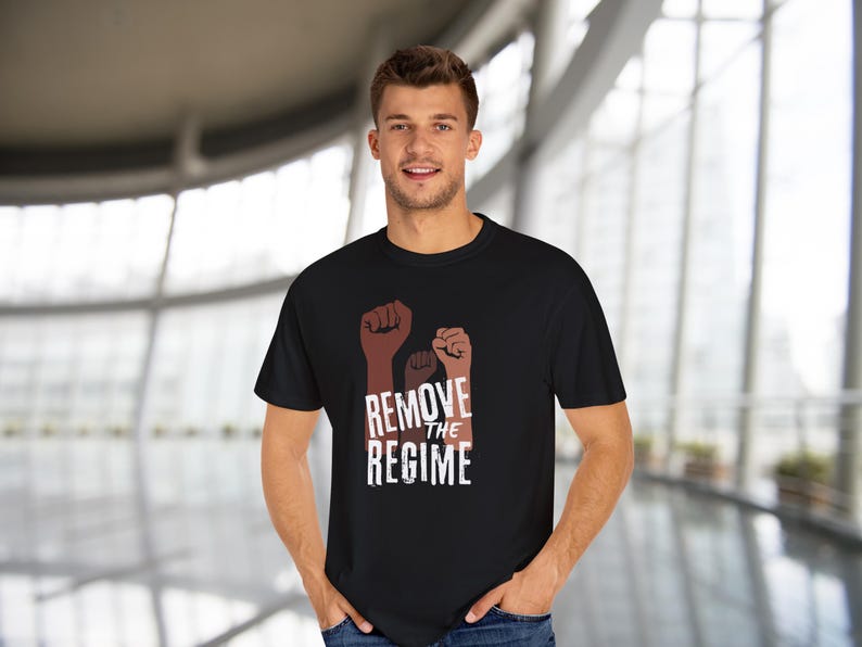 May include: Black t-shirt featuring three raised fists in shades of brown, with the words "REMOVE THE REGIME" in white. The shirt is a classic crew neck style.